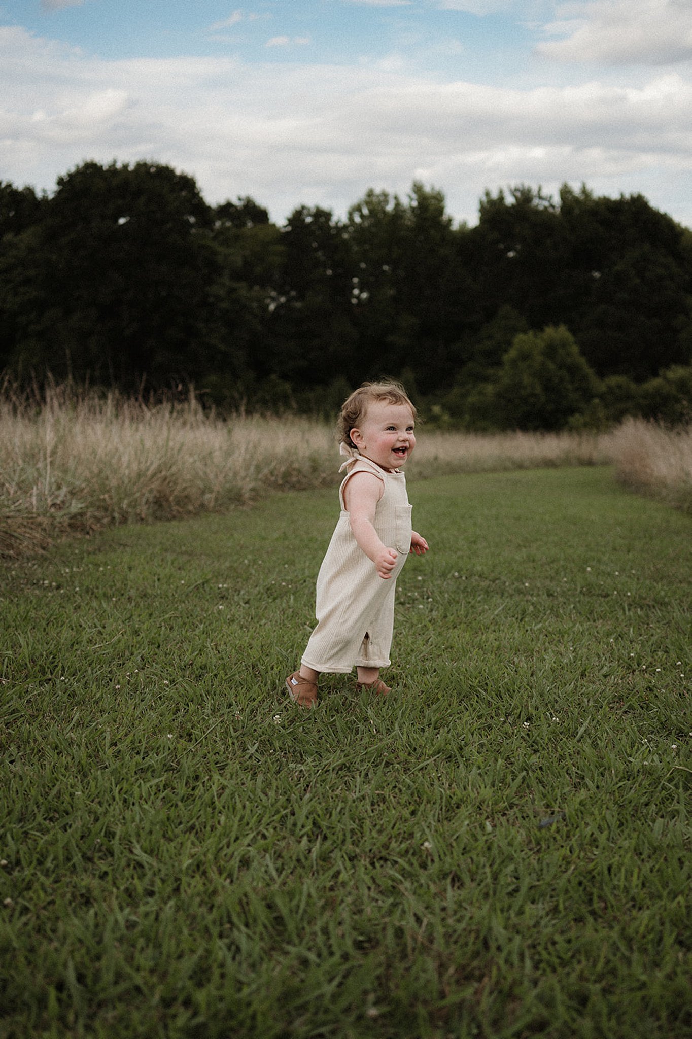 little boy laughing in a field