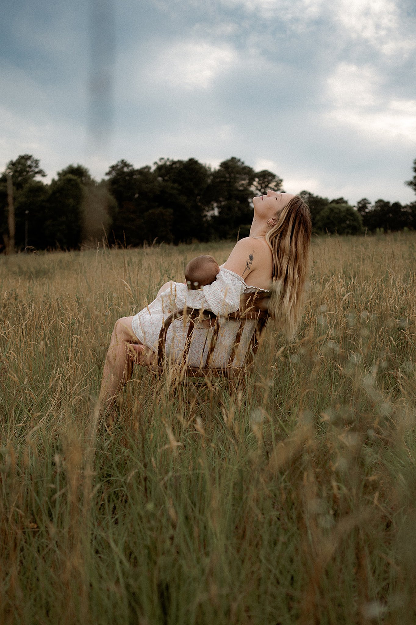mom sitting in a chair breastfeeding her child in a field